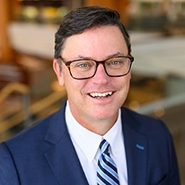 Person wearing glasses and suit smiling 