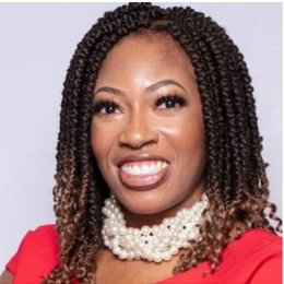 Person wearing red top and pearl necklace smiling