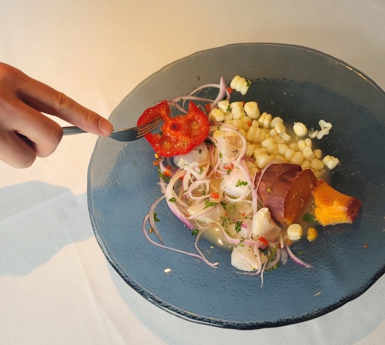 A hand holding a fork prepares to dive into an artistically arranged dish of food. 