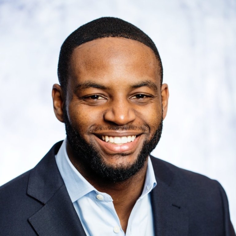 A man in a suit and dress shirt smiles for a photo.