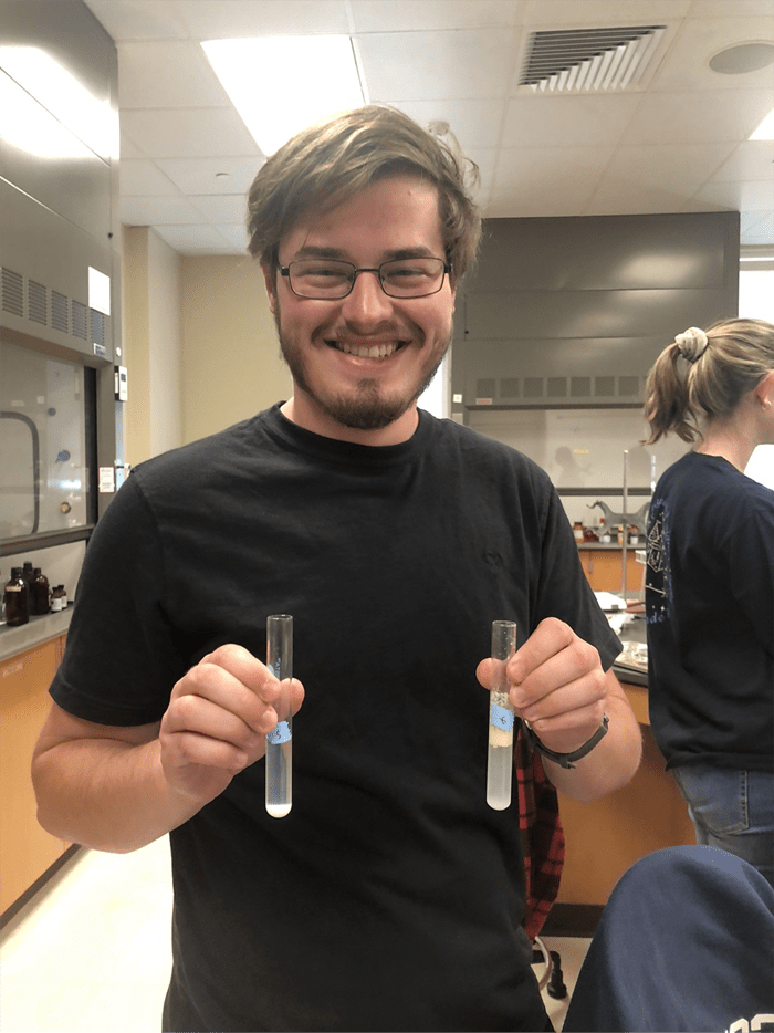 McGinnis holding up two test tubes during a lab. One is more active than the other.