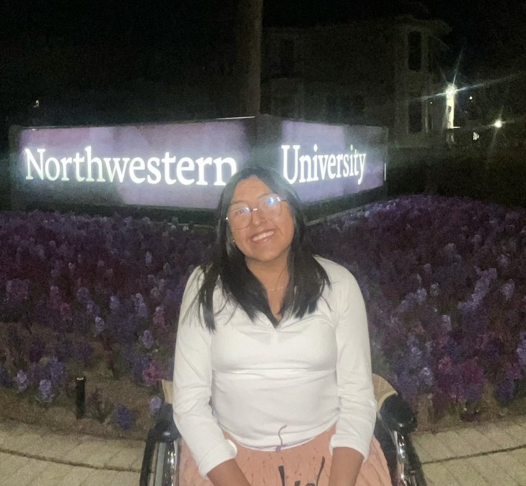 Vale Wiñay Quispe smiles for a photo in front of the Northwestern University sign.