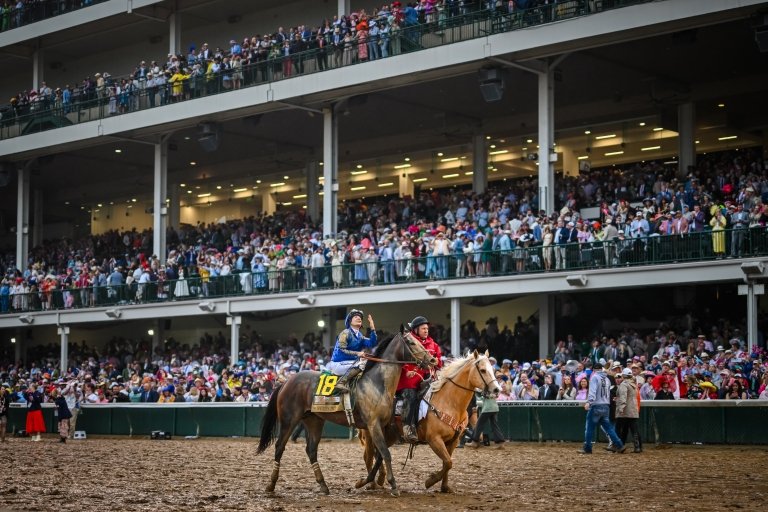 Junior Alvarado looks up to the sky on top of a muddy Sovereignty after winning the Kentucky Derby.
