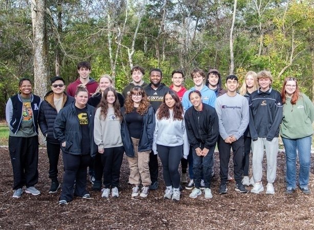 About 20 Kessler Scholars pose for a photos in the forest.