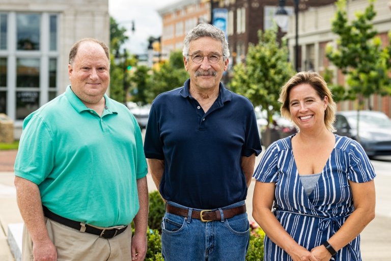 Two men and a woman post for a photo in front of the buildings located along Main Street in downtown Danville, Kentucky. 