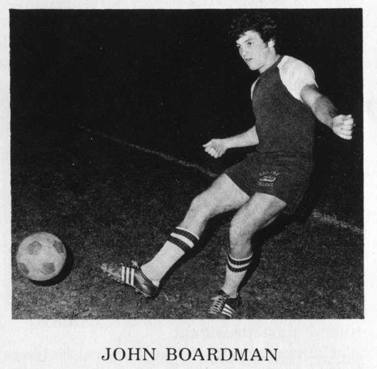 A black-and-white photo shows a man kicking a soccer ball.