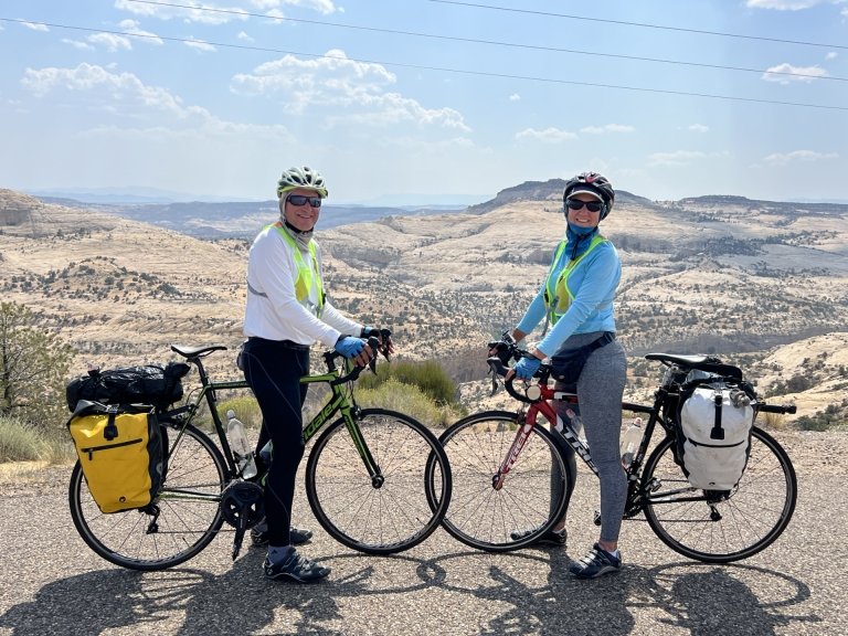 Sarah Murray and her husband with their bikes in front of a desert background