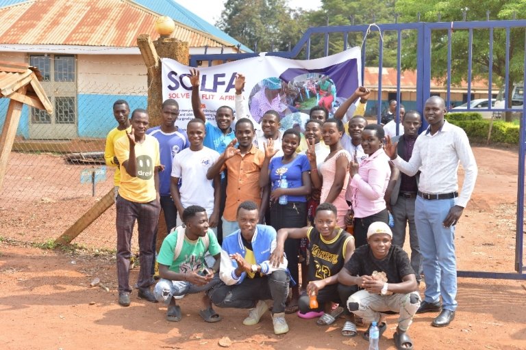 A group of refugees pose in front of a SOLFA banner.