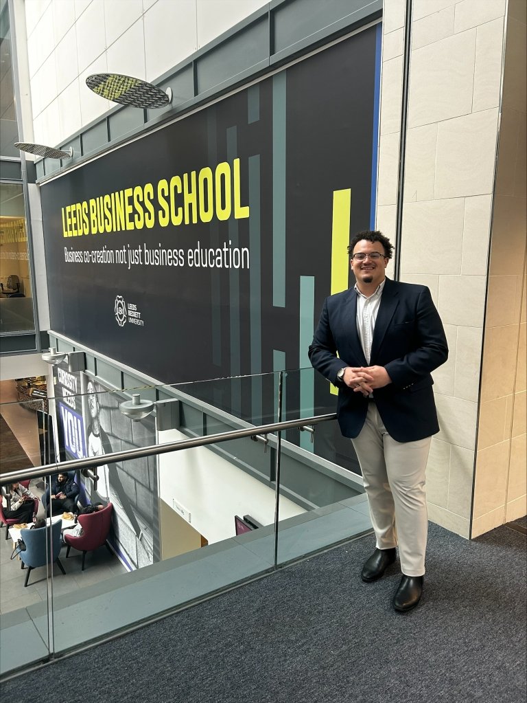 Aiden Jackson poses in front of a sign for Leeds Business school while pursing his MBA in England. 