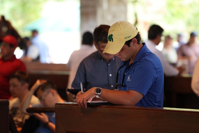 Centre College student Catesby Clay makes notes on a clipboard while assessing horses at an auction. 