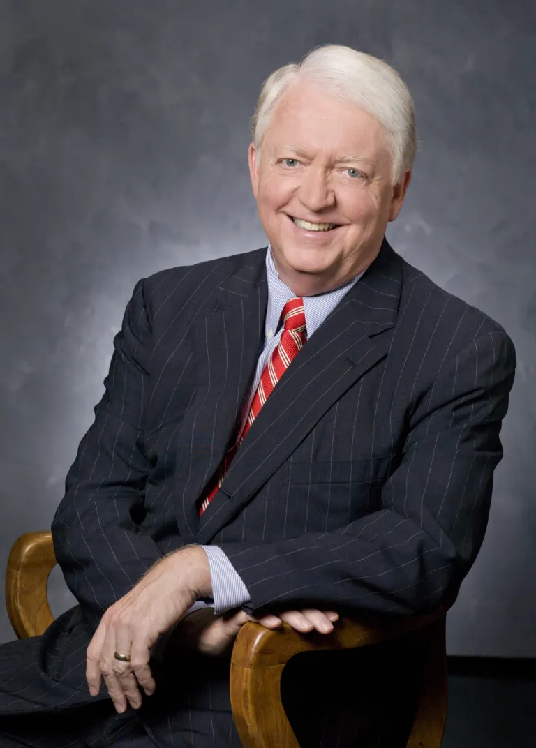 Former Centre College President Michael F. Adams photos for a photo in a dark, pin-striped suit. 