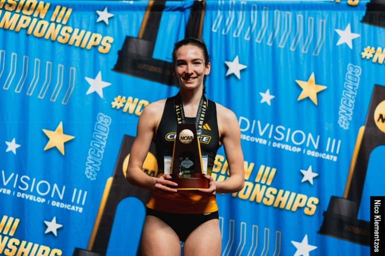 Serena McNeilly standing on the podium, smiling and holding her trophy.