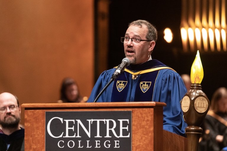 Provost and Vice President for Academic Affairs Alex McAllister speaks behind a podium with a Centre College sign while wearing academic regalia during opening convocation&nbsp;