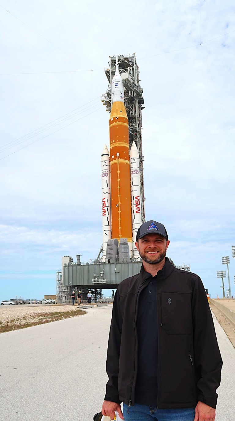 Jimmy Skaggs stands outdoors in front of the Artemis II rocket as it is wheeled out to the launch pad prior to liftoff&nbsp;