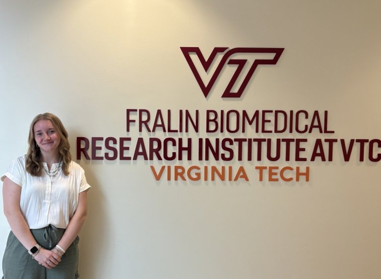 Caroline Toler next to a sign that says "Fralin Biomedical Research Institute At VTC Virginia Tech"