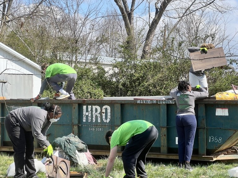 Centre College students gather debris from a home and deposit it in a large dumpster&nbsp;trailer 