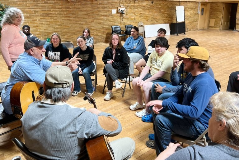 Centre College students sit in a group with local West Virginia residents holding musical instruments&nbsp;