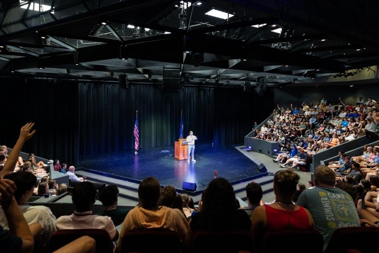 High school students in an auditorium raise their hands to ask questions as Kentucky Gov. Andy Beshear speaks into a microphone at Centre College's Norton Center for the Arts. 