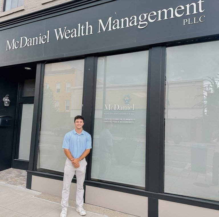 Harris Phelps poses for a photo in front of a building that says "McDaniel Wealth Management PLLC."