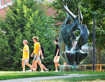 Students walking on campus near flame statue