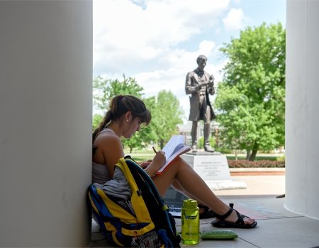 Student studying at outside library in front of Lincoln statute