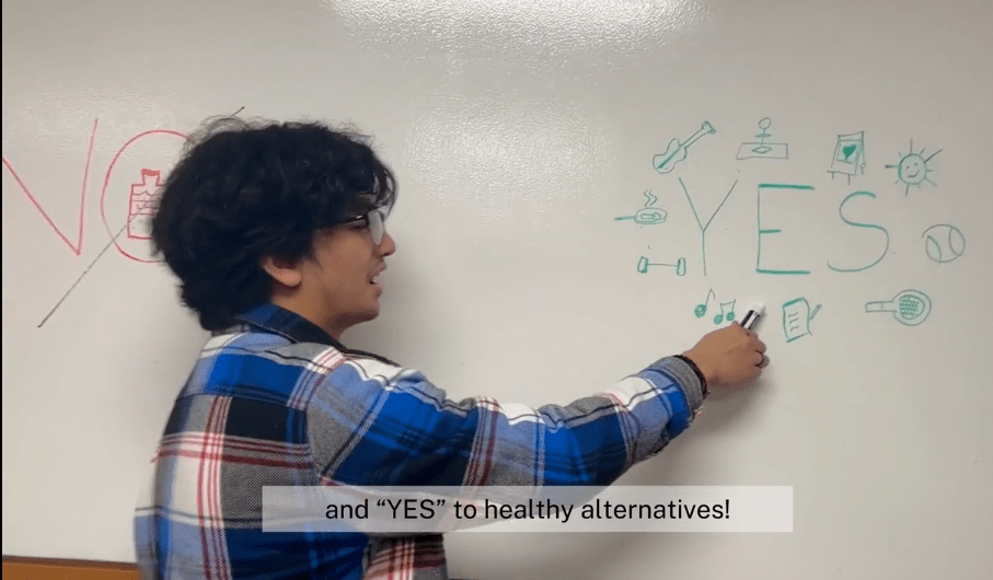 A student points to the word "yes" written on a dry erase board.