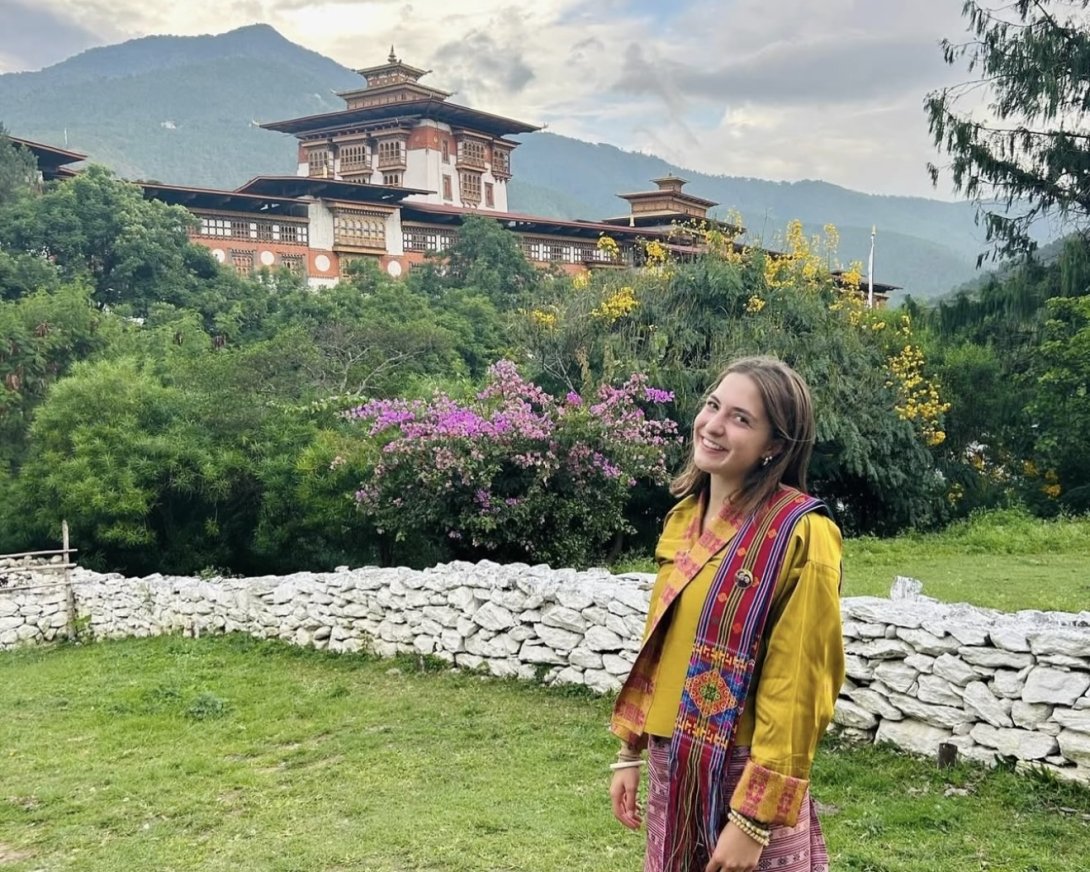 A student studying abroad in Bhutan in front of an historic building in the country.