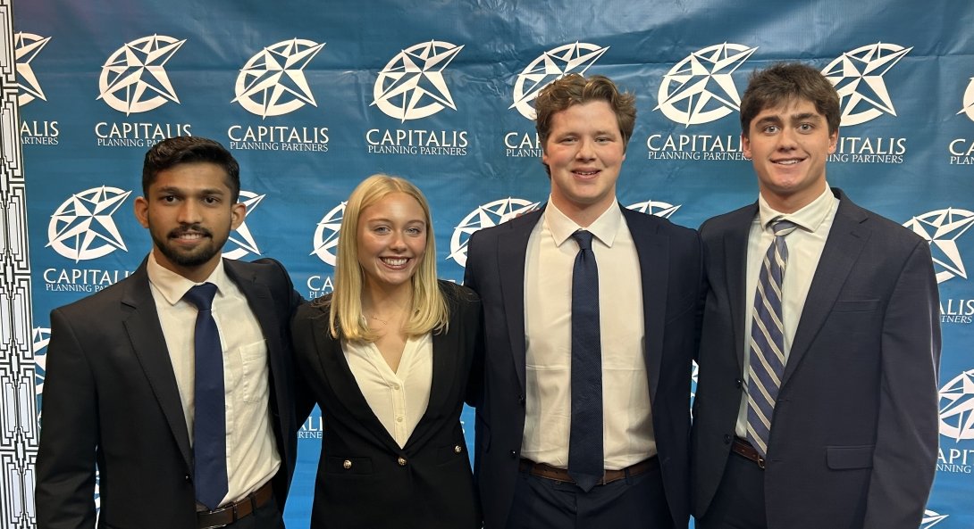 Four students, three men and one woman, wearing business attire, pose for a photo after winning the regional CFA Challenge in Louisville, Kentucky.