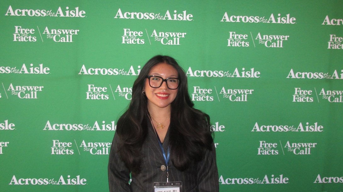 Getzamary Solano in front of an Across the Aisle backdrop during an Ambassador weekend.